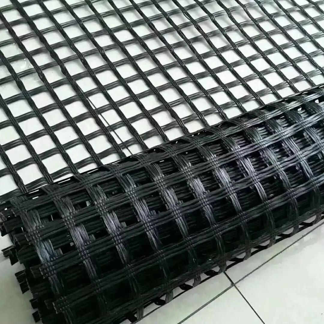 土工格栅产品展示,黑色网格状材料,平整铺设在地面上,阳光照射下清晰显示其结构